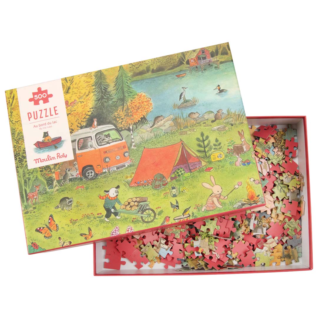 De open Moulin Roty legpuzzeldoos met deksel en losse puzzelstukjes erin.