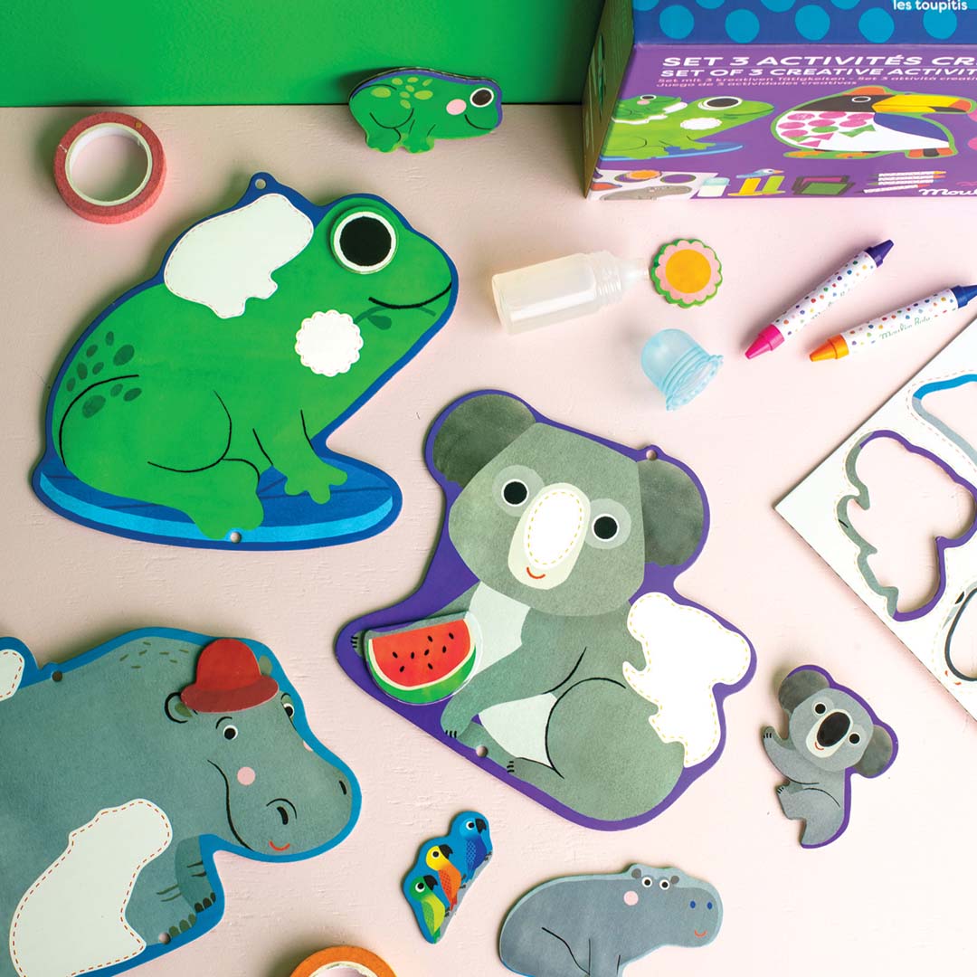 Onderdelen van de Moulin Roty knutselset met uitgesneden dierenfiguren zoals een kikker, koala en nijlpaard, en stiften.