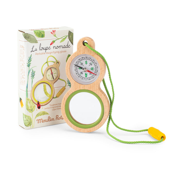 Moulin Roty houten vergrootglas met kompas en groene draagkoord, naast de productverpakking.
