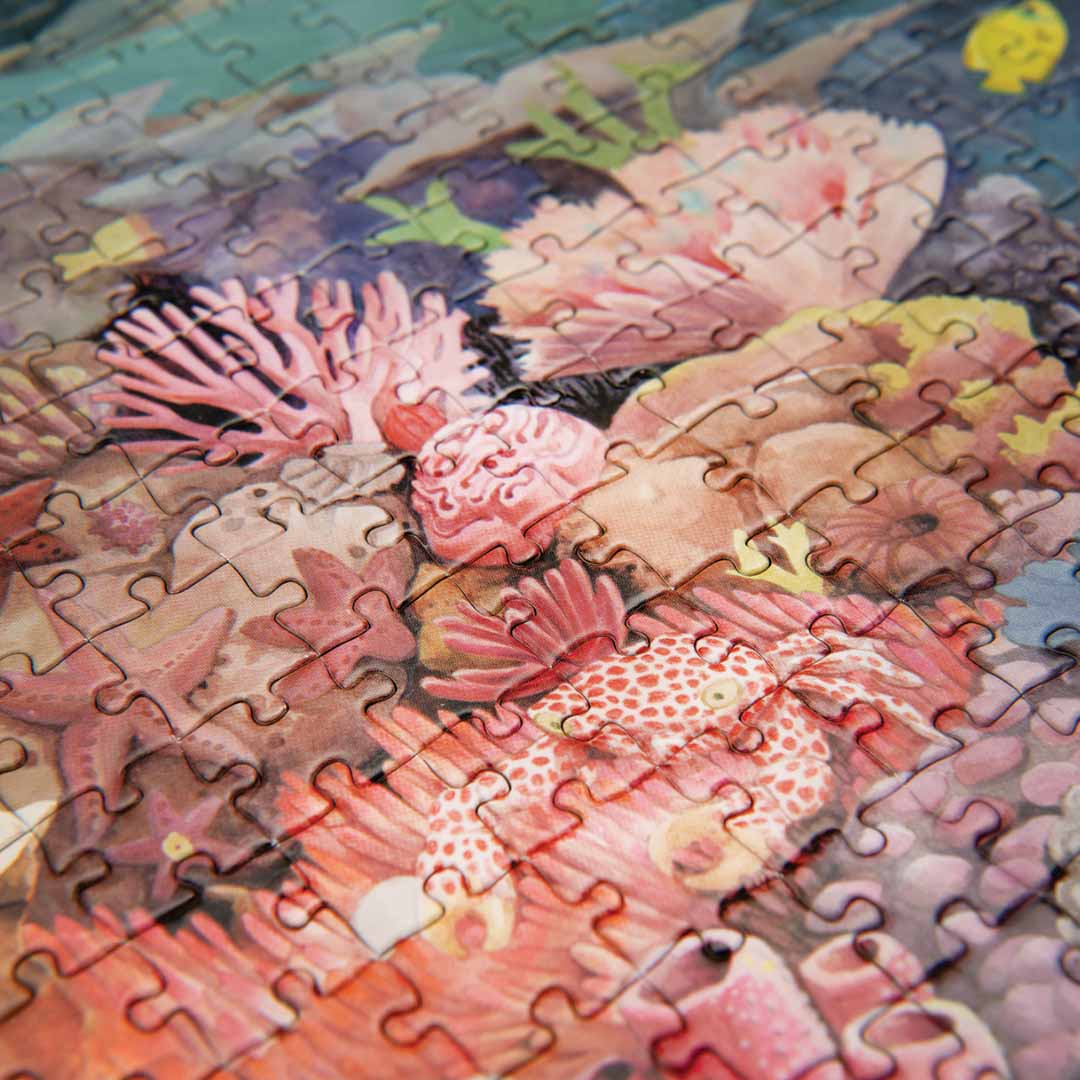 Detail van de Moulin Roty legpuzzel met verschillende koralen en een gevlekte krab.