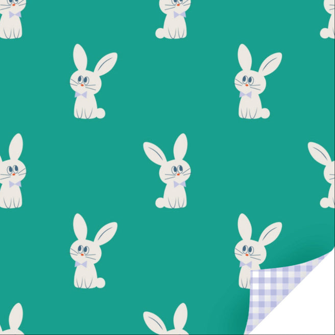Ole inpakpapier met een patroon van witte konijnen op een groene achtergrond en een omgevouwen hoek die een paars geruit patroon toont.
