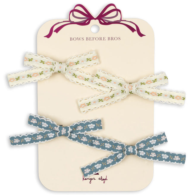 Konges Sløjd haarclips Leonora Bow, een set van vier gebloemde haarstrikken in crème en blauw op een kartonnen verpakking.