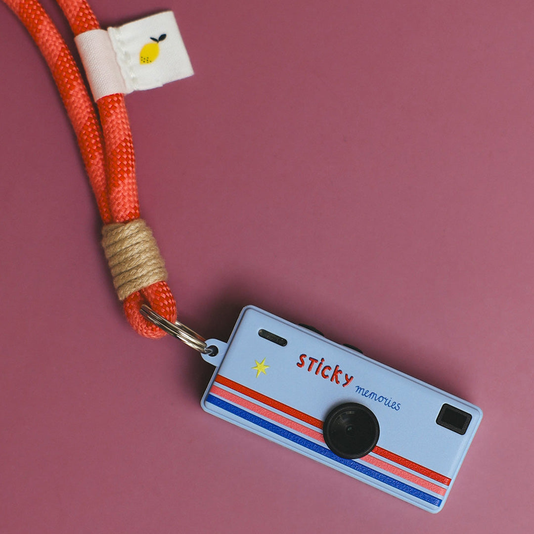 Detailopname van de blauwe Sticky Lemon mini kindercamera met roze draagkoord.