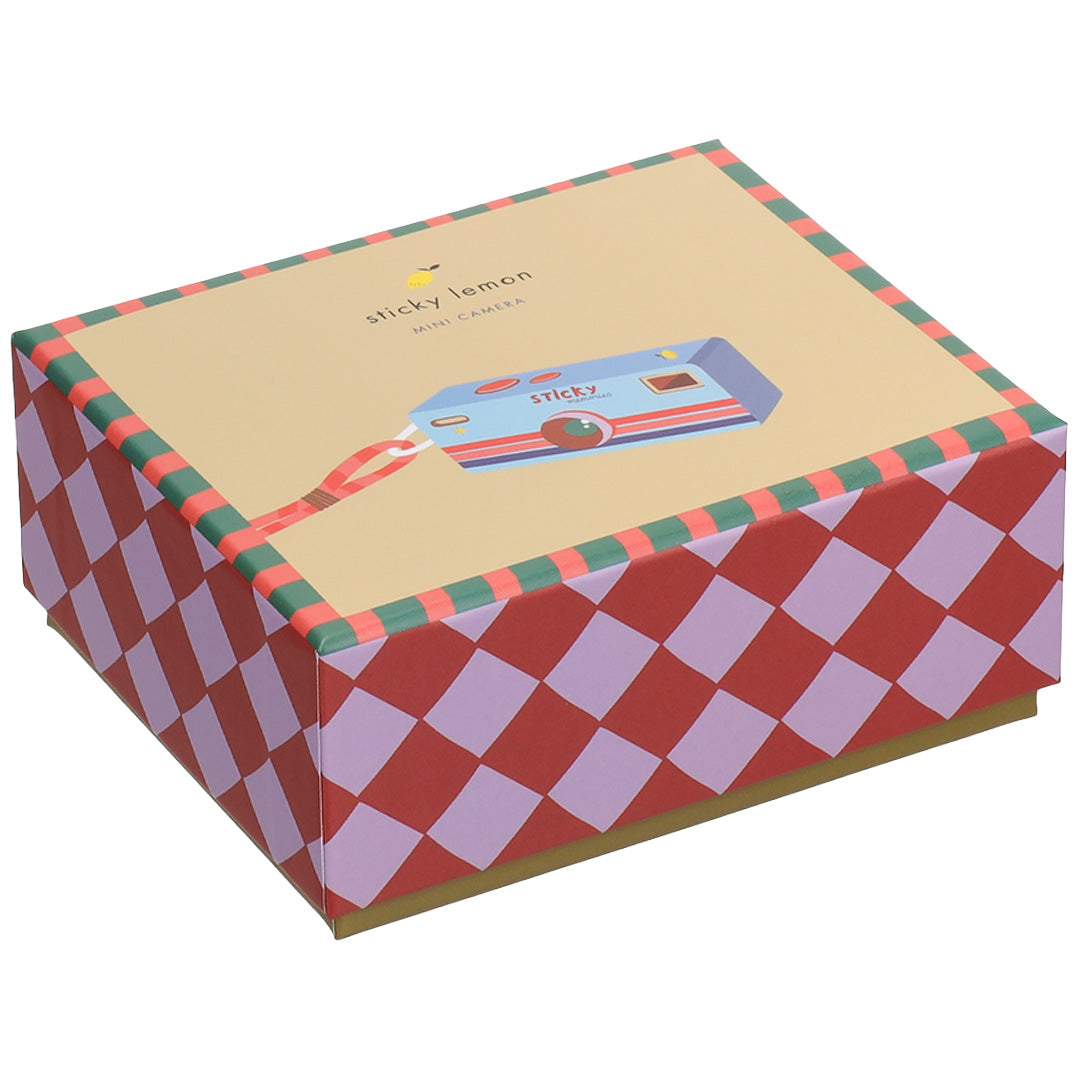 De gesloten verpakking van de Sticky Lemon mini kindercamera met een ruitjespatroon op de zijkanten.