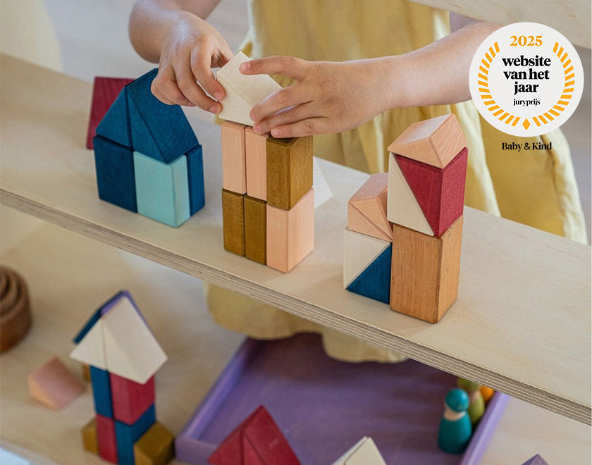 kind speelt met kleurrijke houten bouwblokken van Grimm's 